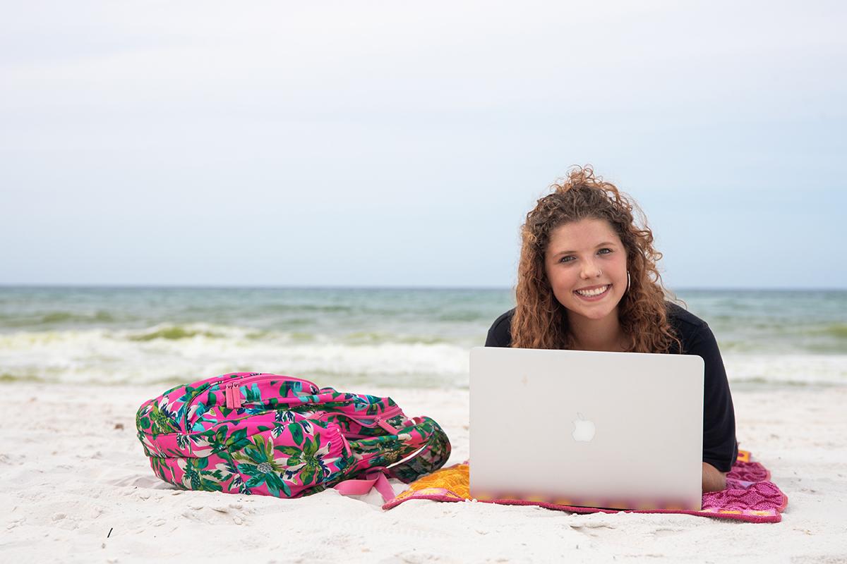 Student with laptop on the beach
